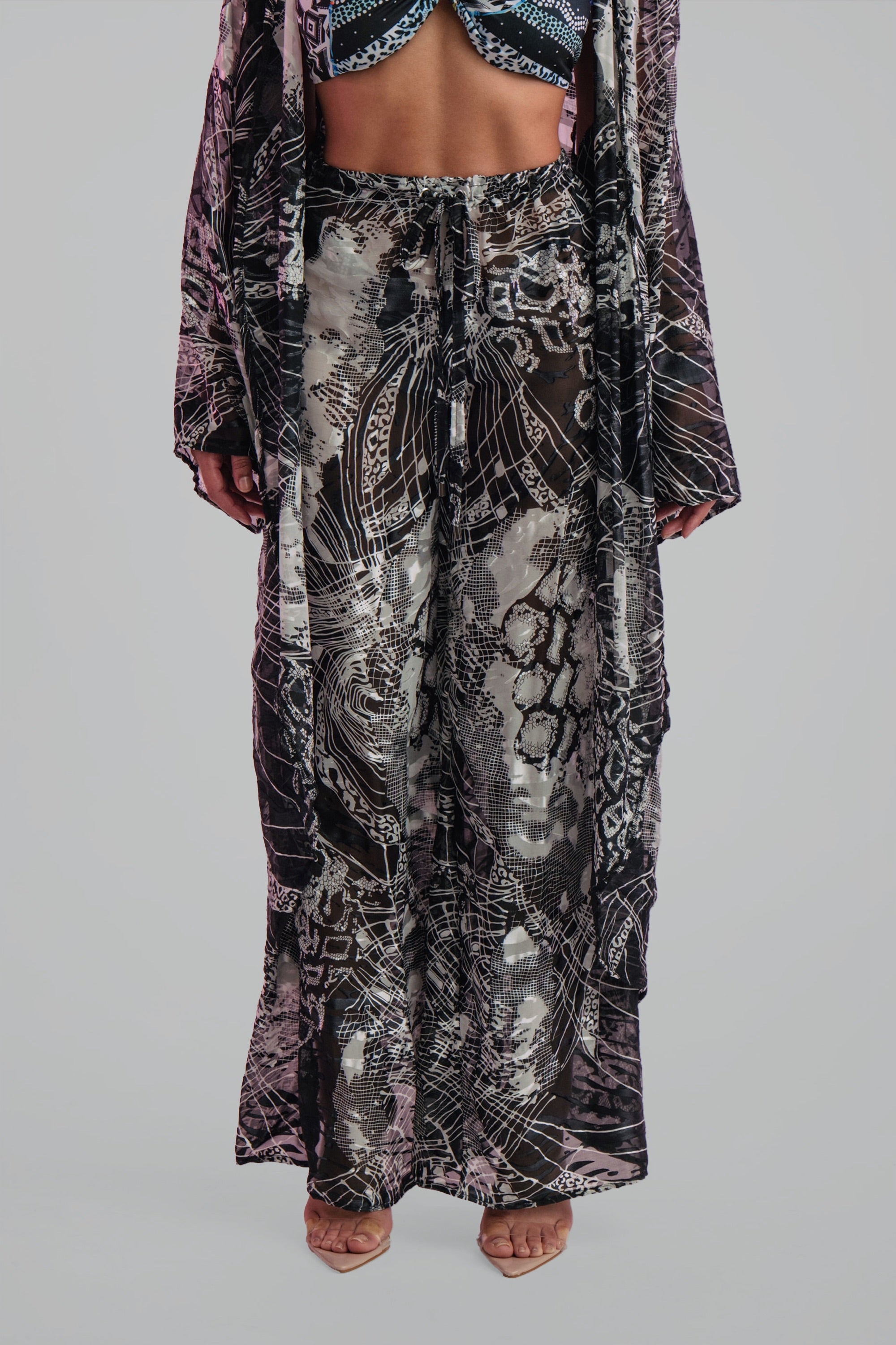 Woman wearing a wide leg black and white patterned pants set on a plain background