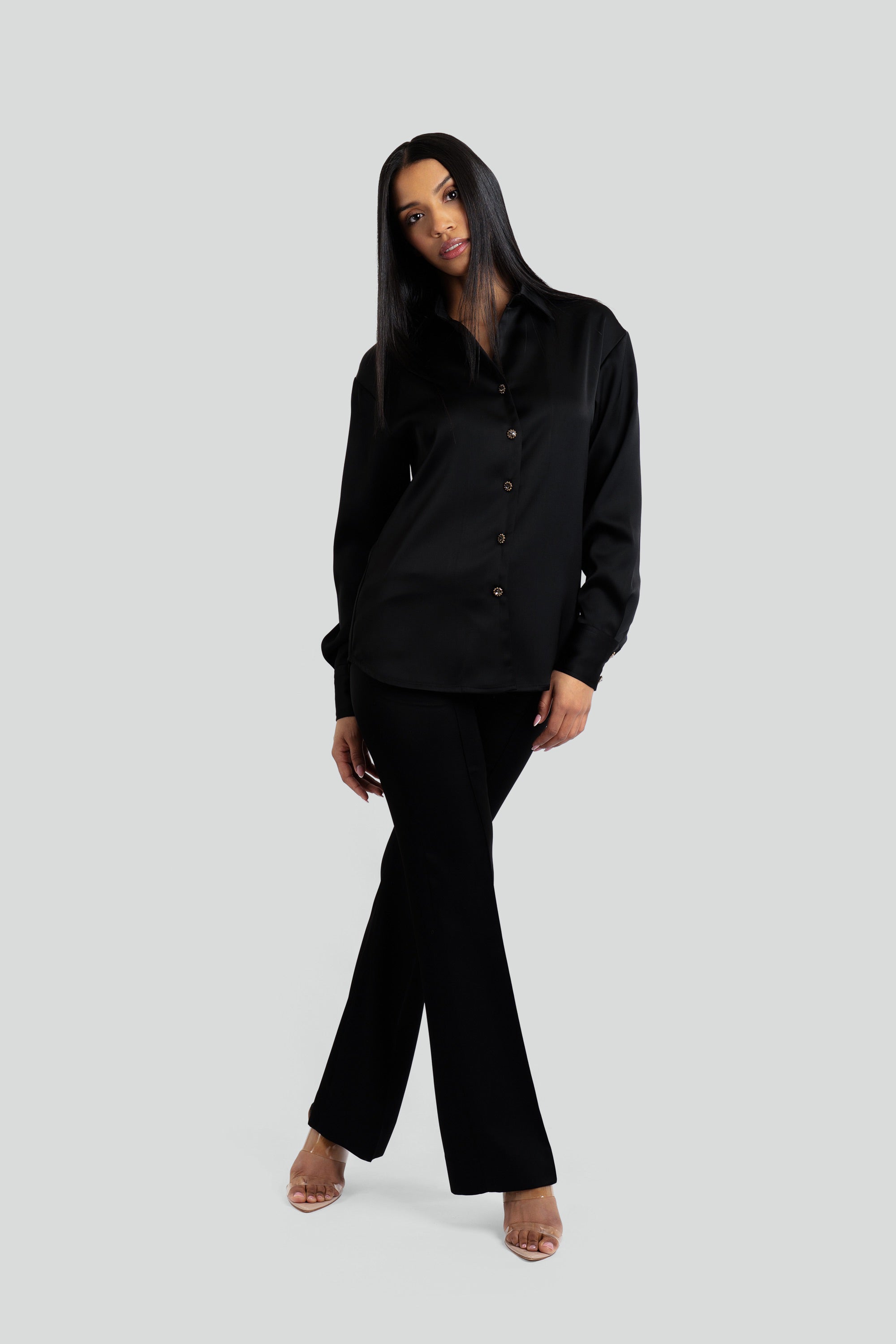 Person wearing a black satin shirt and pants on a white background