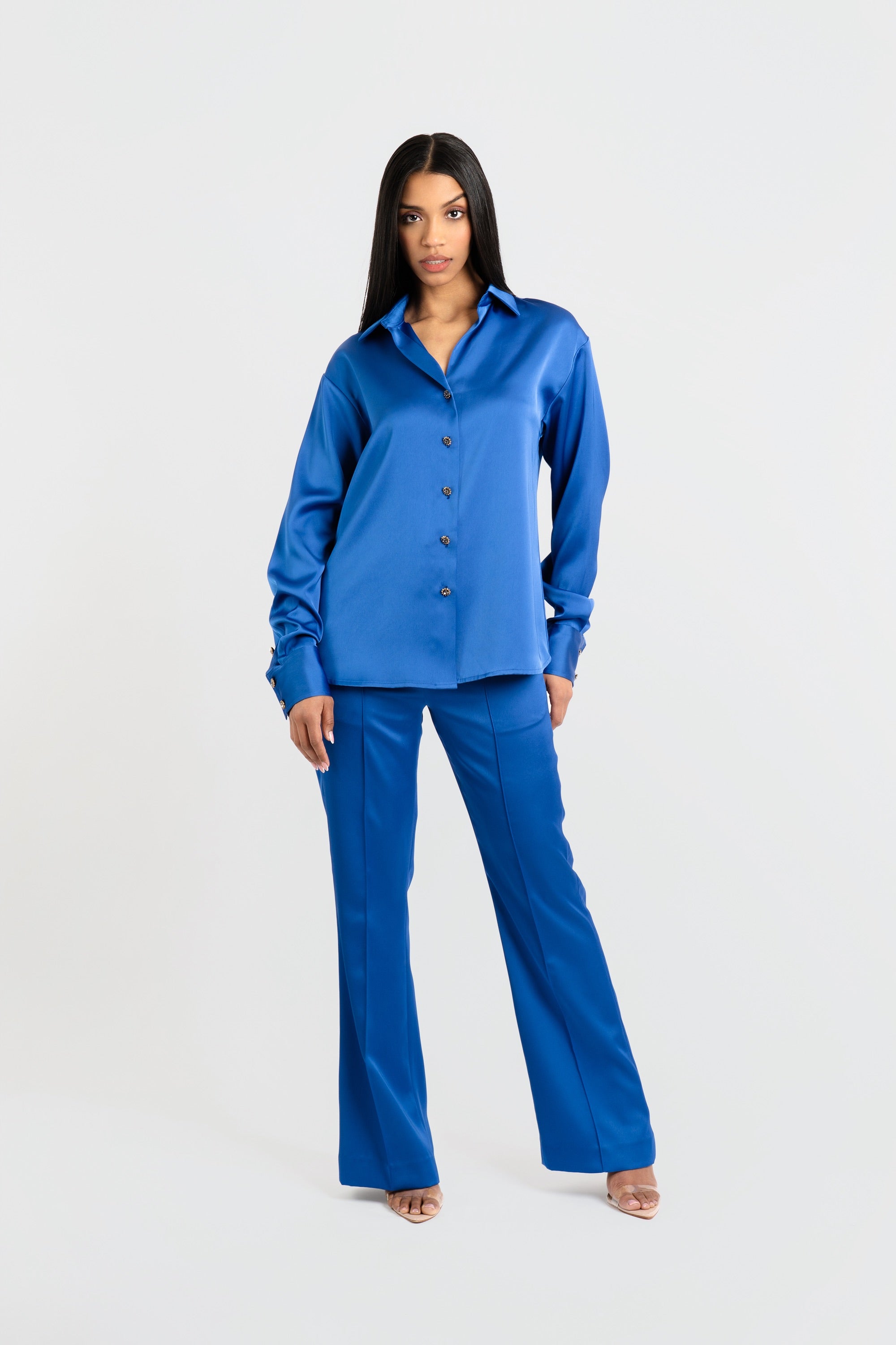 Woman wearing a blue satin shirt and pants set on a white background