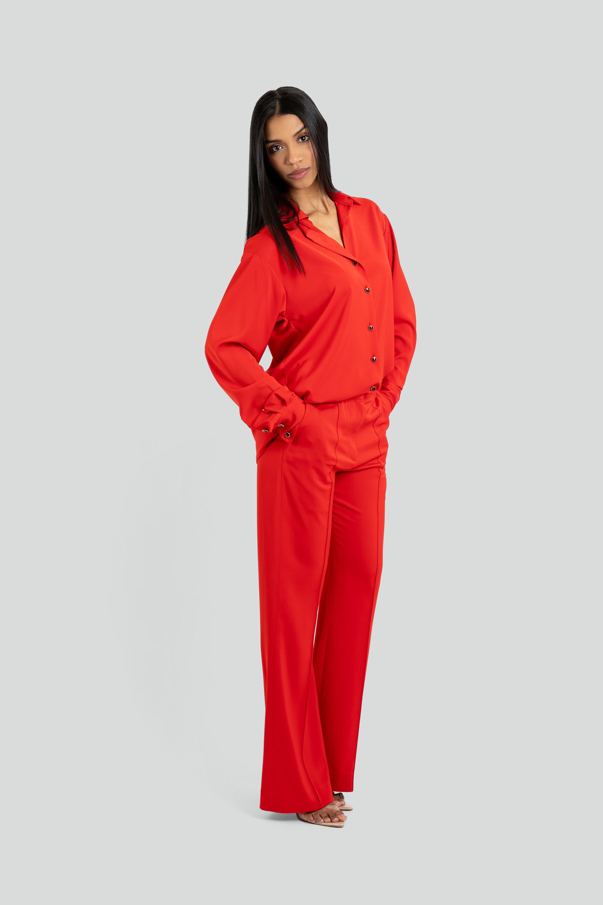 Person wearing a red satin shirt and pants set on a white background