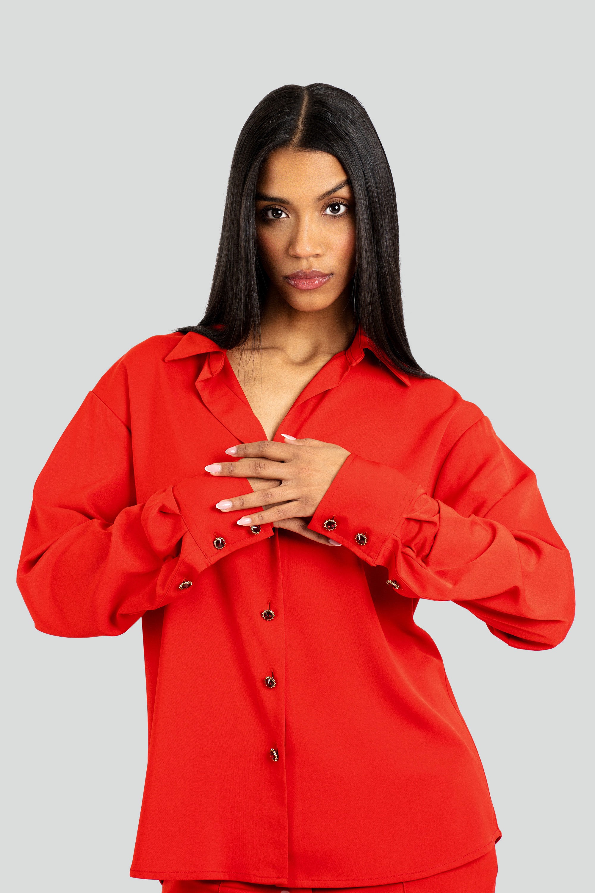 Woman wearing a red satin shirt and pants set on a white background