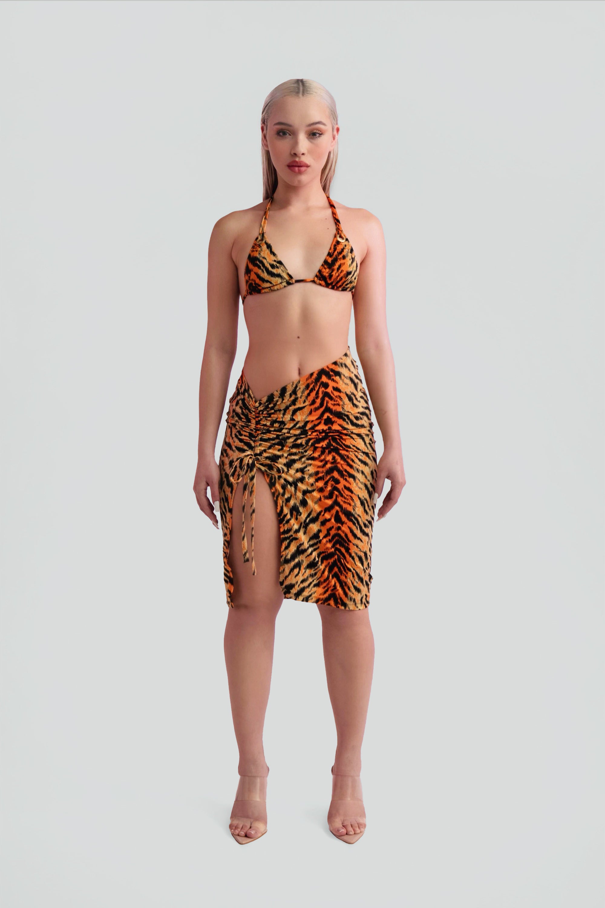 Woman wearing a tiger print bikini and skirt on a gray background