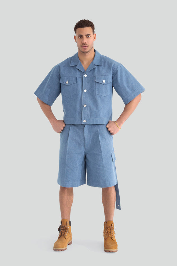 Man wearing a denim tailored short suit set featuring a structured short sleeve blazer jacket and matching straight leg tailored shorts