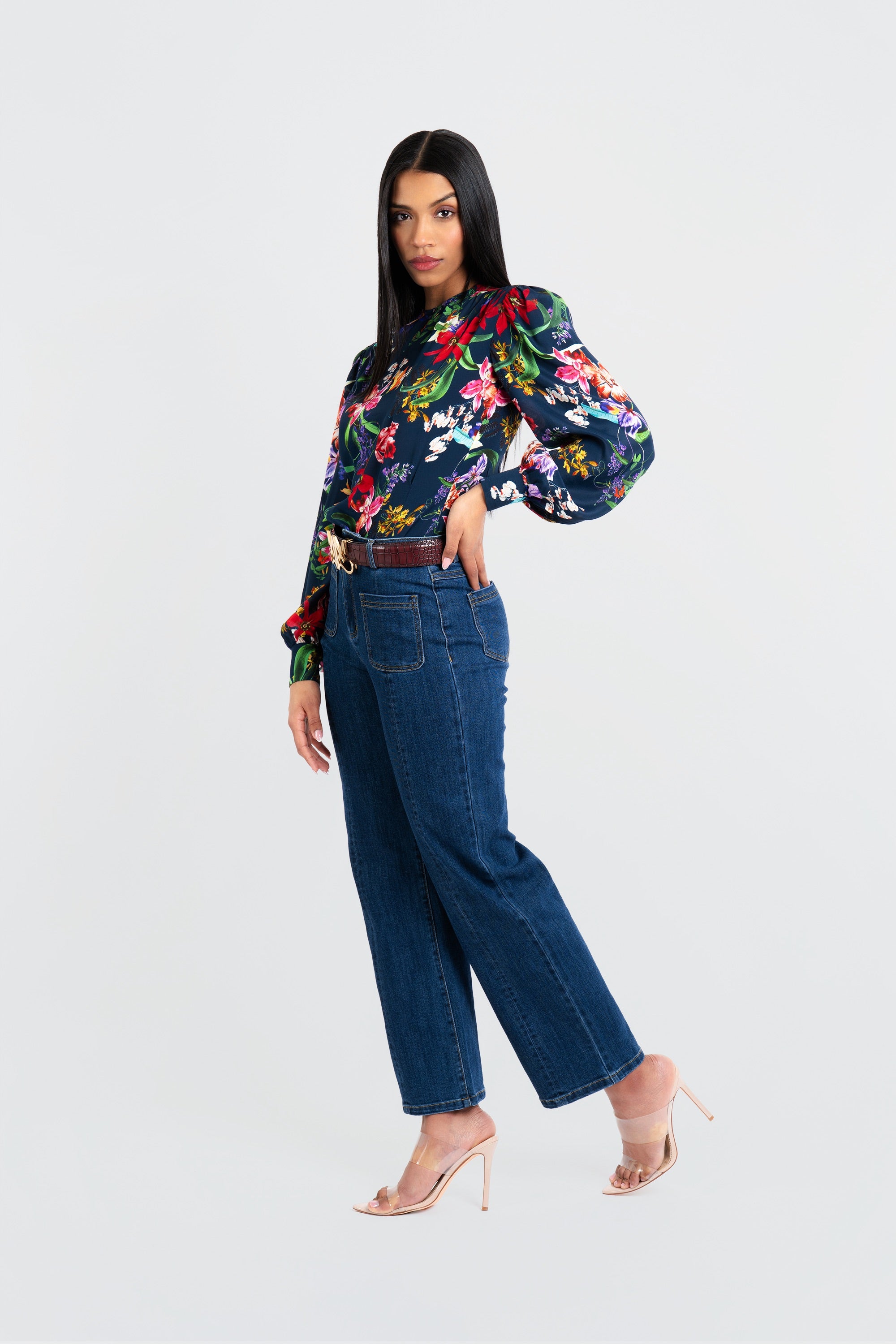 Woman wearing a floral blouse and blue jeans on a white background