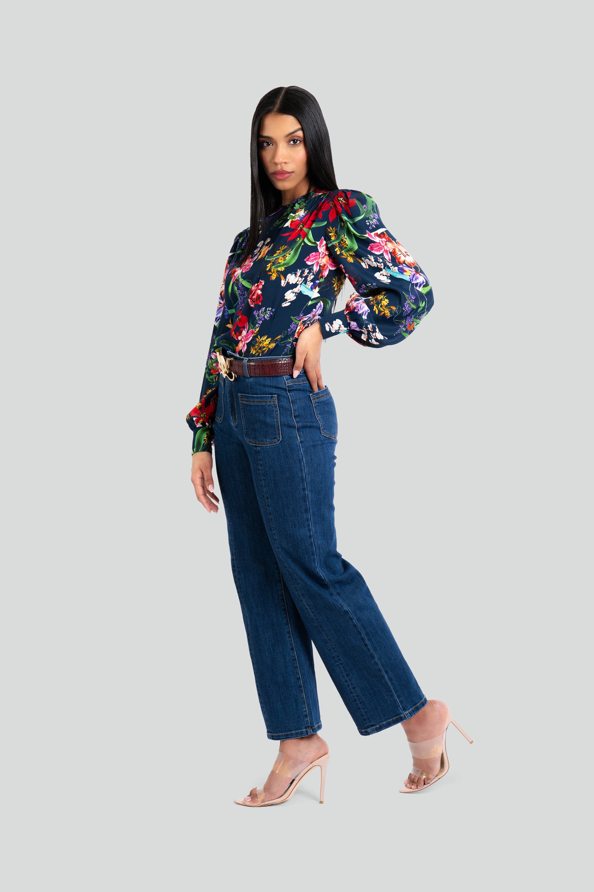 Woman wearing a floral blouse and blue jeans on a white background
