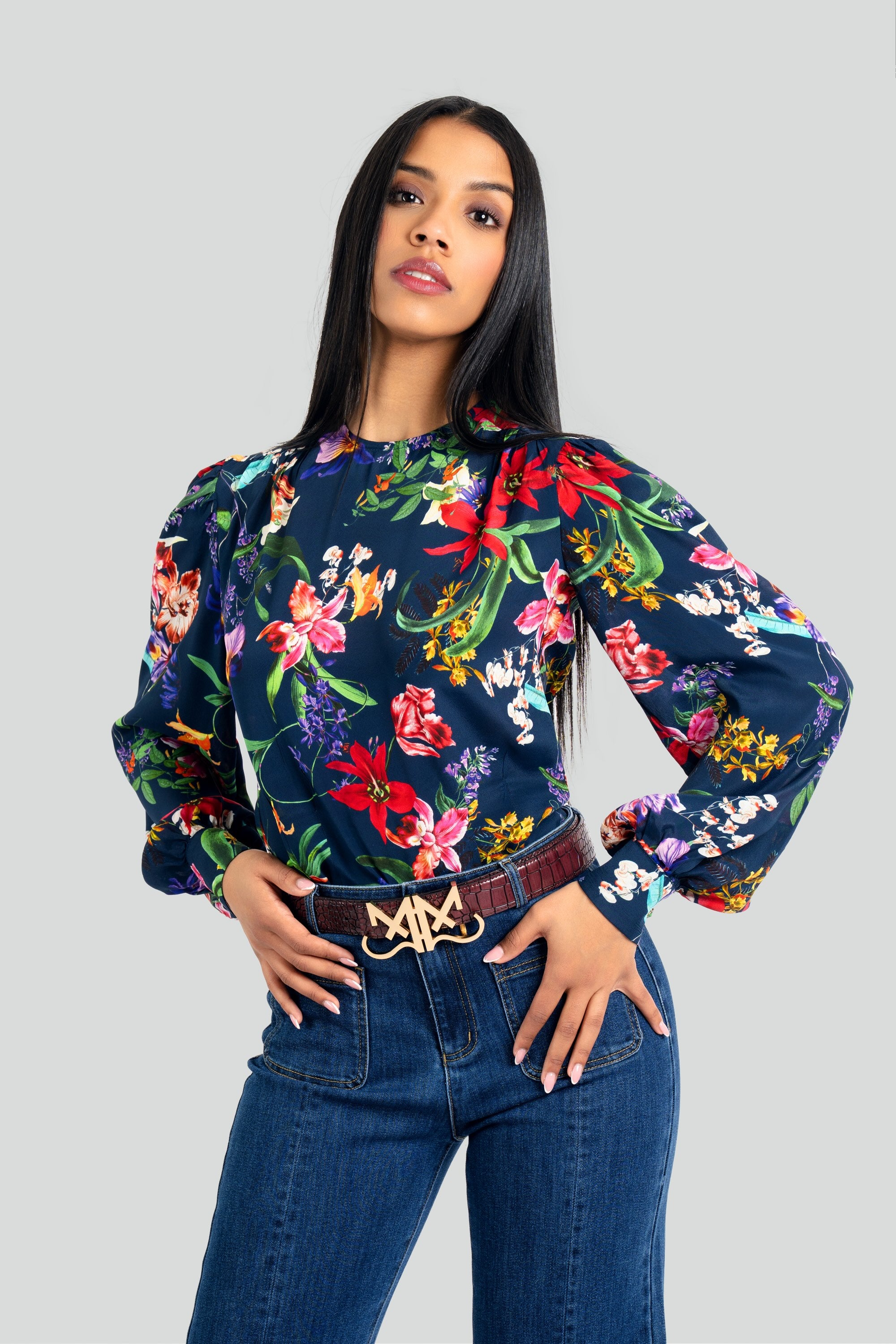 Model posing in a Maui by Lolita vibrant floral print long-sleeve top featuring sparkling rhinestone buttons