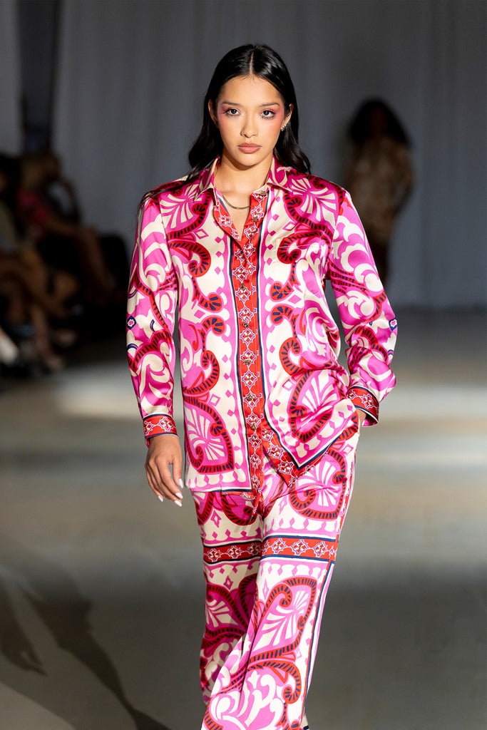Model wearing a white and pink patterned outfit on a runway