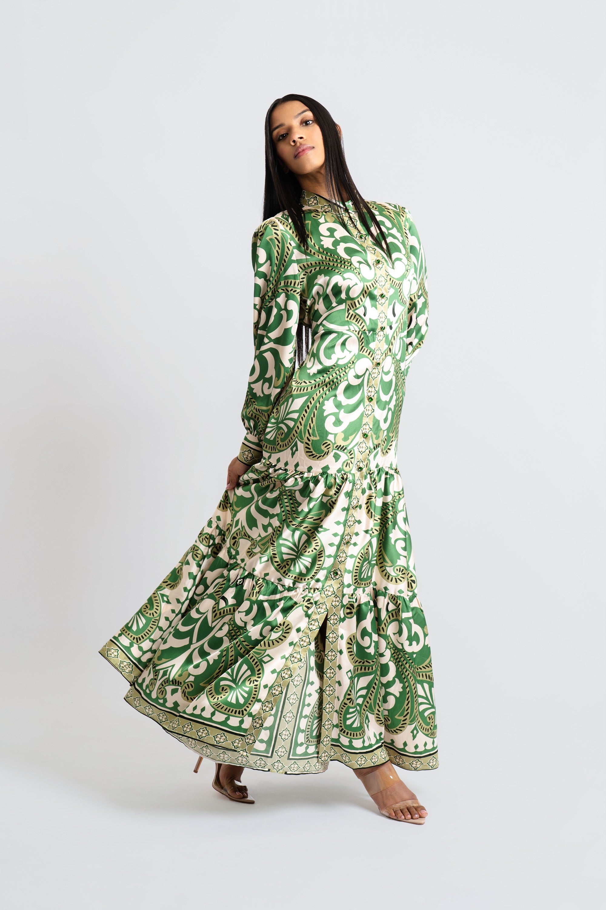 Woman wearing an emerald and cream baroque-inspired print maxi dress with voluminous sleeves and skirt posing against a white background